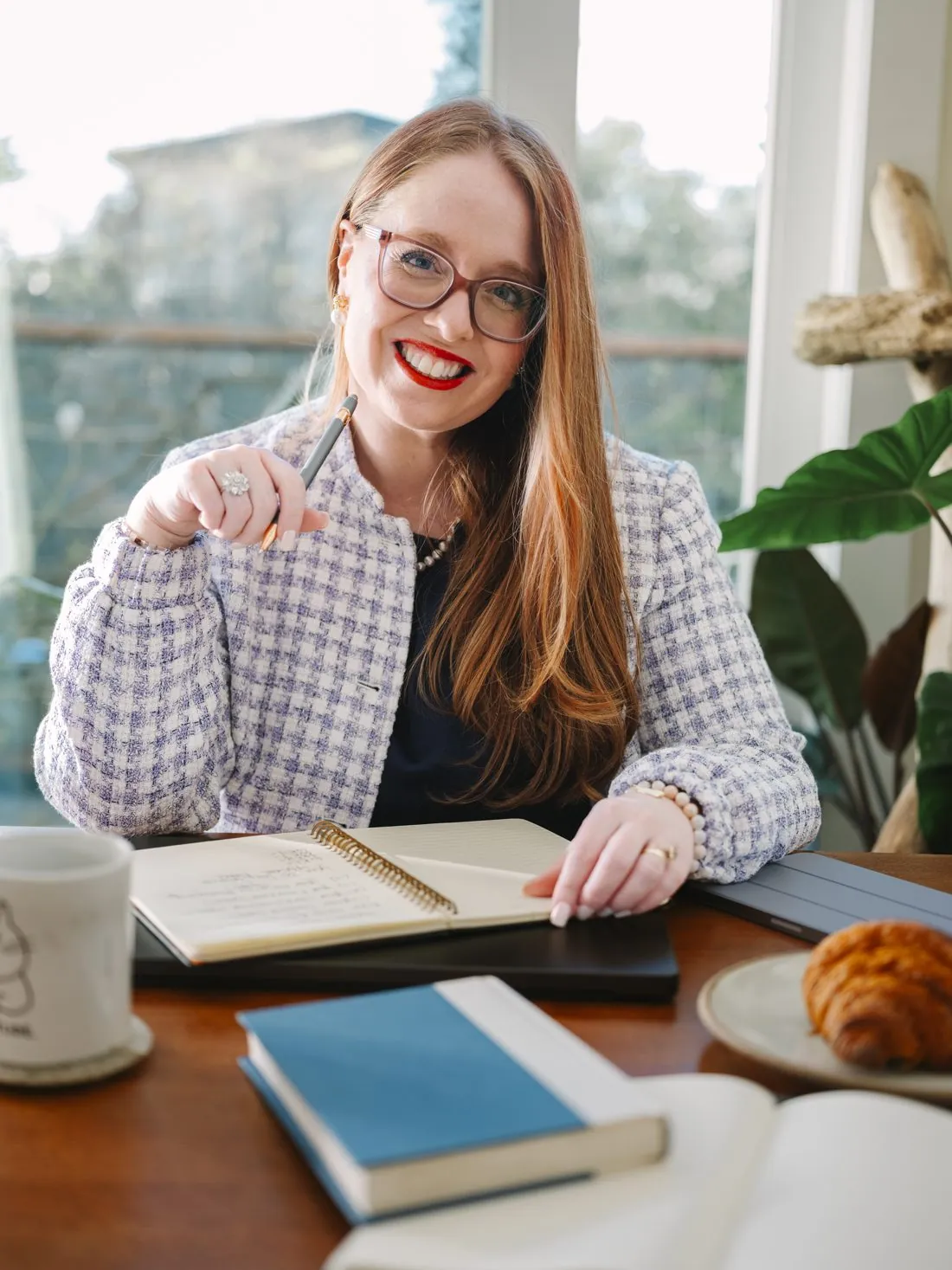 Dr. Monica Rysavy smiling at a desk by a window, notebook open
